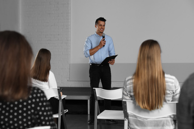 Photo of Male business trainer giving lecture in conference room with projection screen