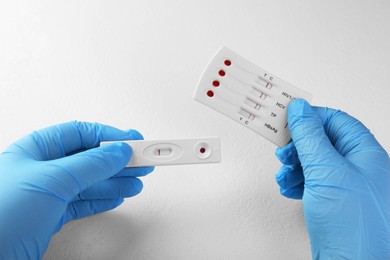 Photo of Doctor holding two disposable express tests at white table, closeup