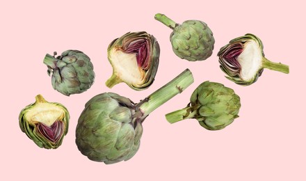 Image of Fresh raw artichokes falling on pink background