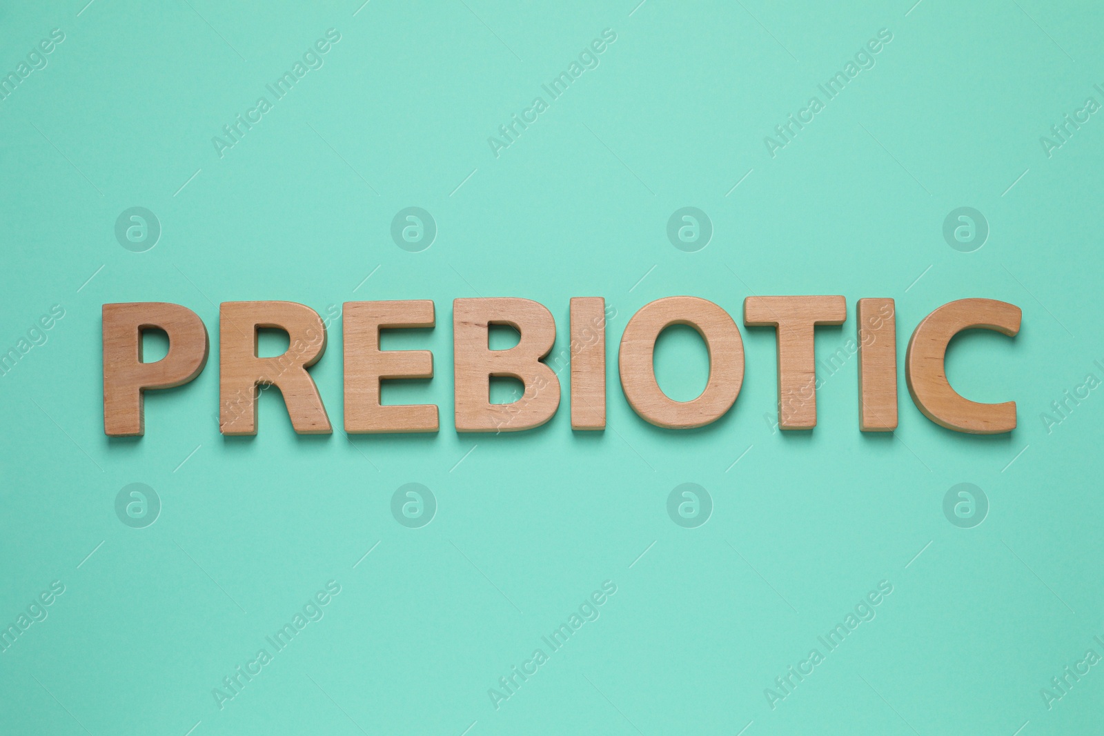 Photo of Word Prebiotic made of wooden letters on turquoise table, flat lay