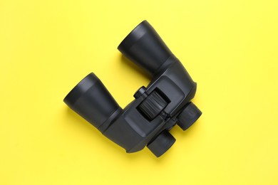 Photo of Modern binoculars on yellow background, top view