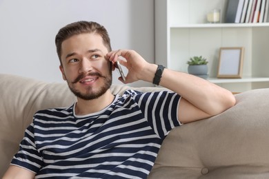 Photo of Happy man talking on smartphone in cozy room