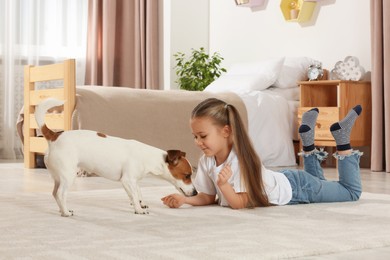 Cute girl with her dog on floor at home. Adorable pet