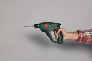 Photo of Man with power drill on grey background, closeup