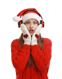 Young woman in Santa hat listening to Christmas music on white background