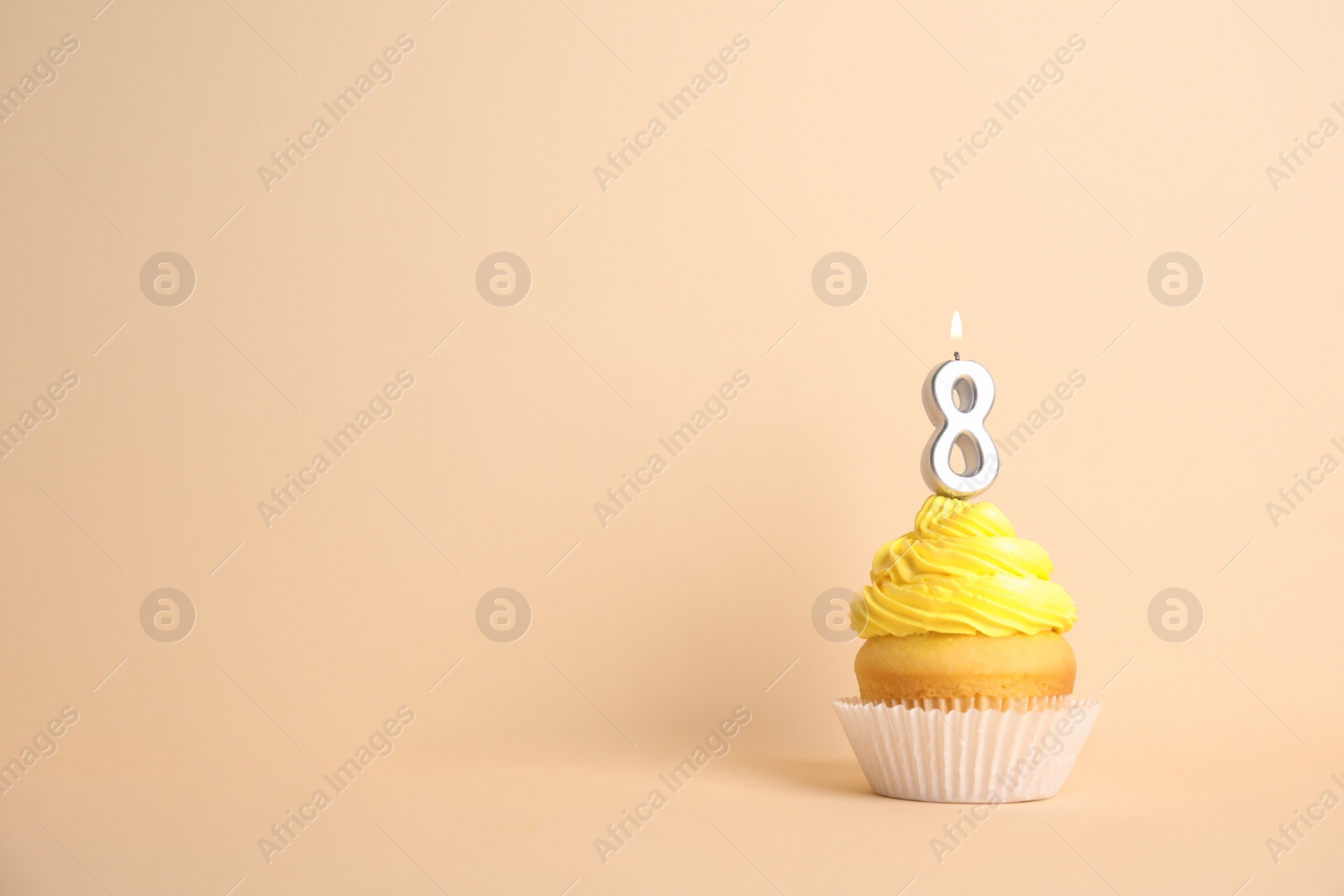 Photo of Birthday cupcake with number eight candle on beige background, space for text