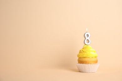 Birthday cupcake with number eight candle on beige background, space for text