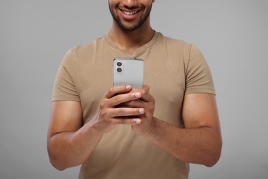 Photo of Man sending message via smartphone on grey background, closeup