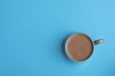 Photo of Delicious cocoa drink in cup on light blue background, top view. Space for text