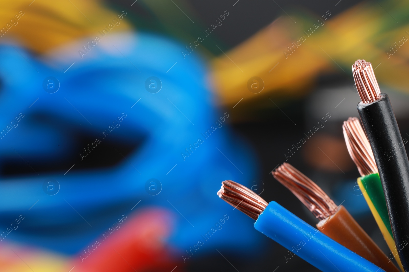 Photo of New colorful electrical wires on blurred background, closeup. Space for text