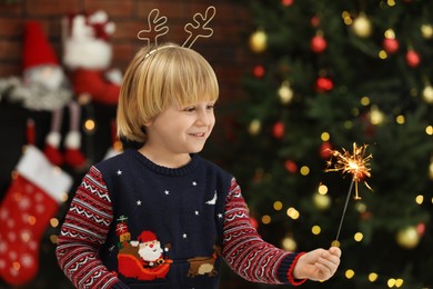 Photo of Little child with burning sparkler at home, space for text. Christmas celebration