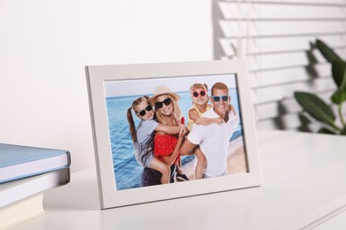 Photo of Frame with family photo on white table indoors, closeup