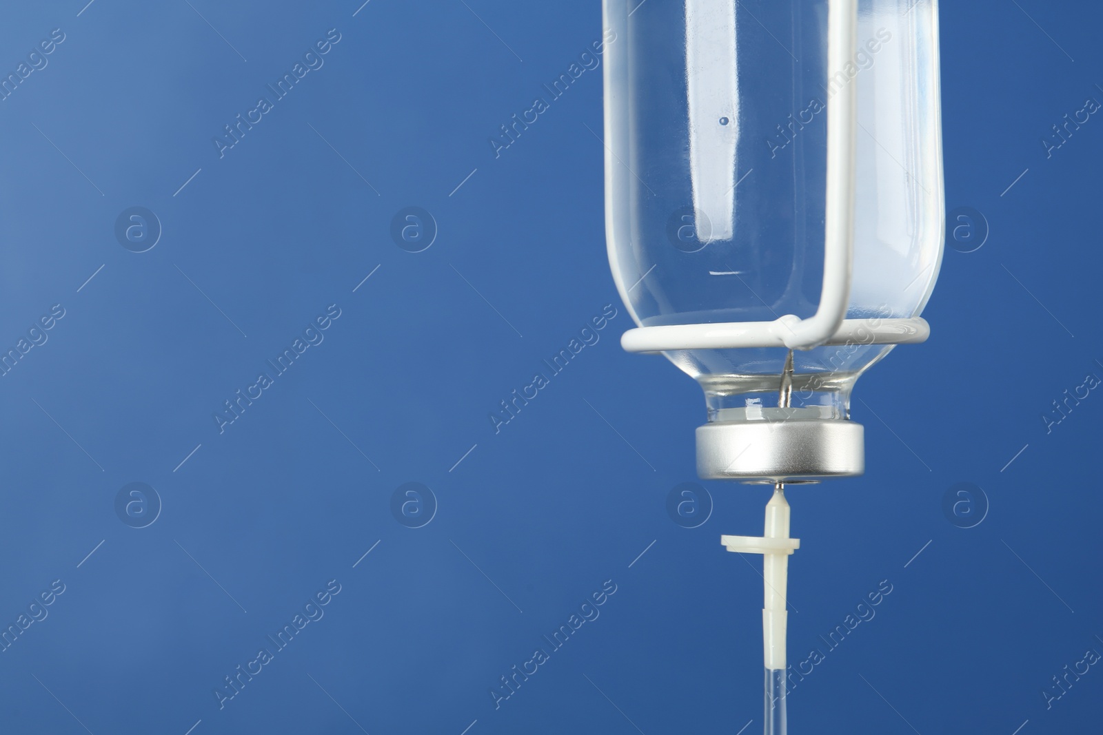 Photo of IV infusion set on blue background, closeup. Space for text