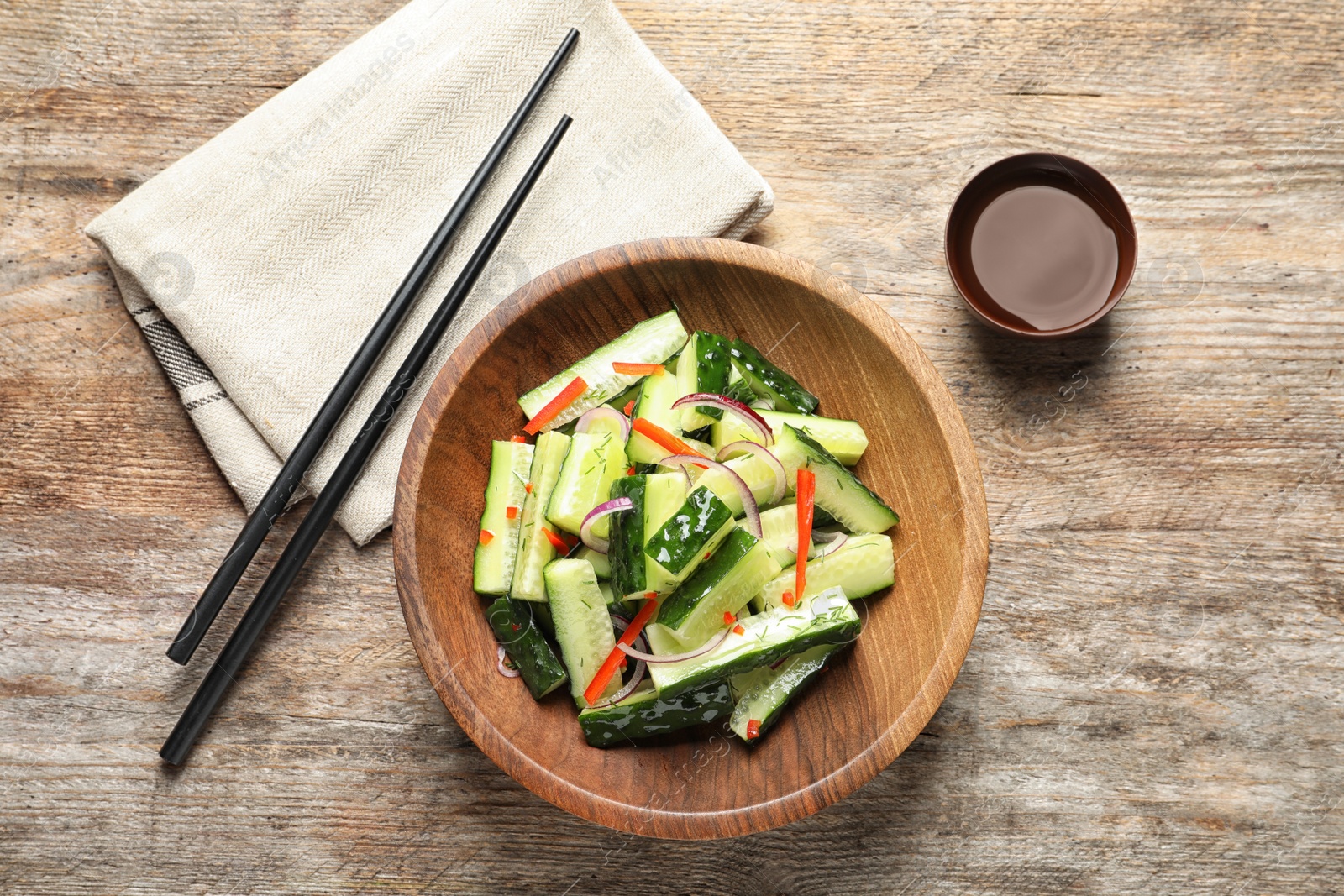 Photo of Plate with delicious cucumber salad served on wooden table, top view