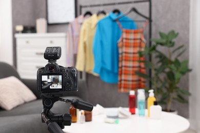 Photo of Beauty blogger's workplace. Cosmetic products and clothes indoors, focus on camera
