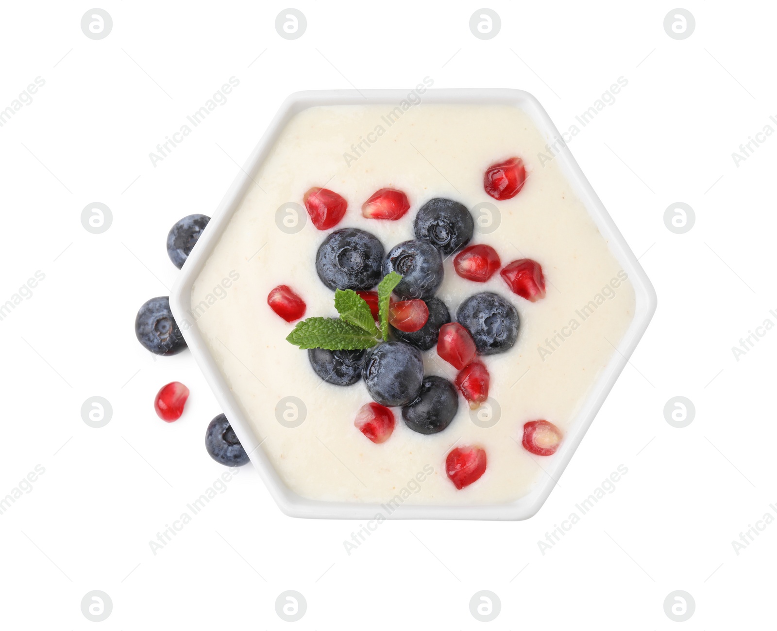 Photo of Bowl of delicious semolina pudding with blueberries, pomegranate and mint isolated on white, top view