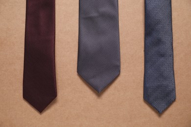 Different neckties on beige background, top view