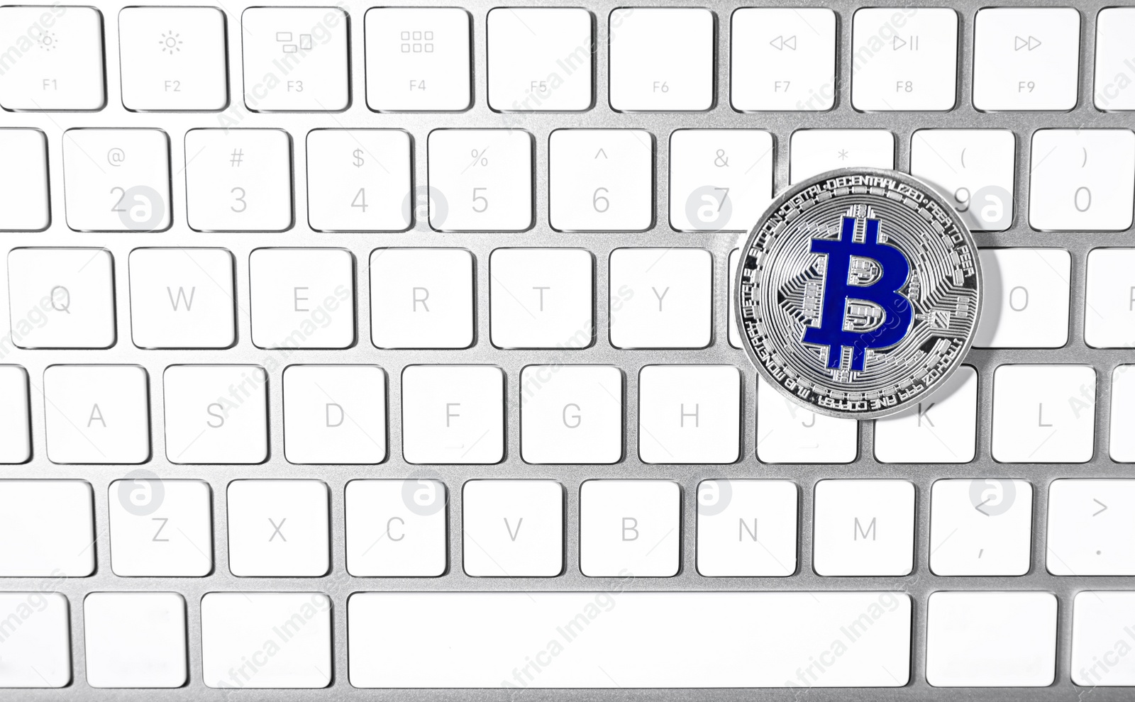 Photo of Silver bitcoin on computer keyboard, top view. Space for text