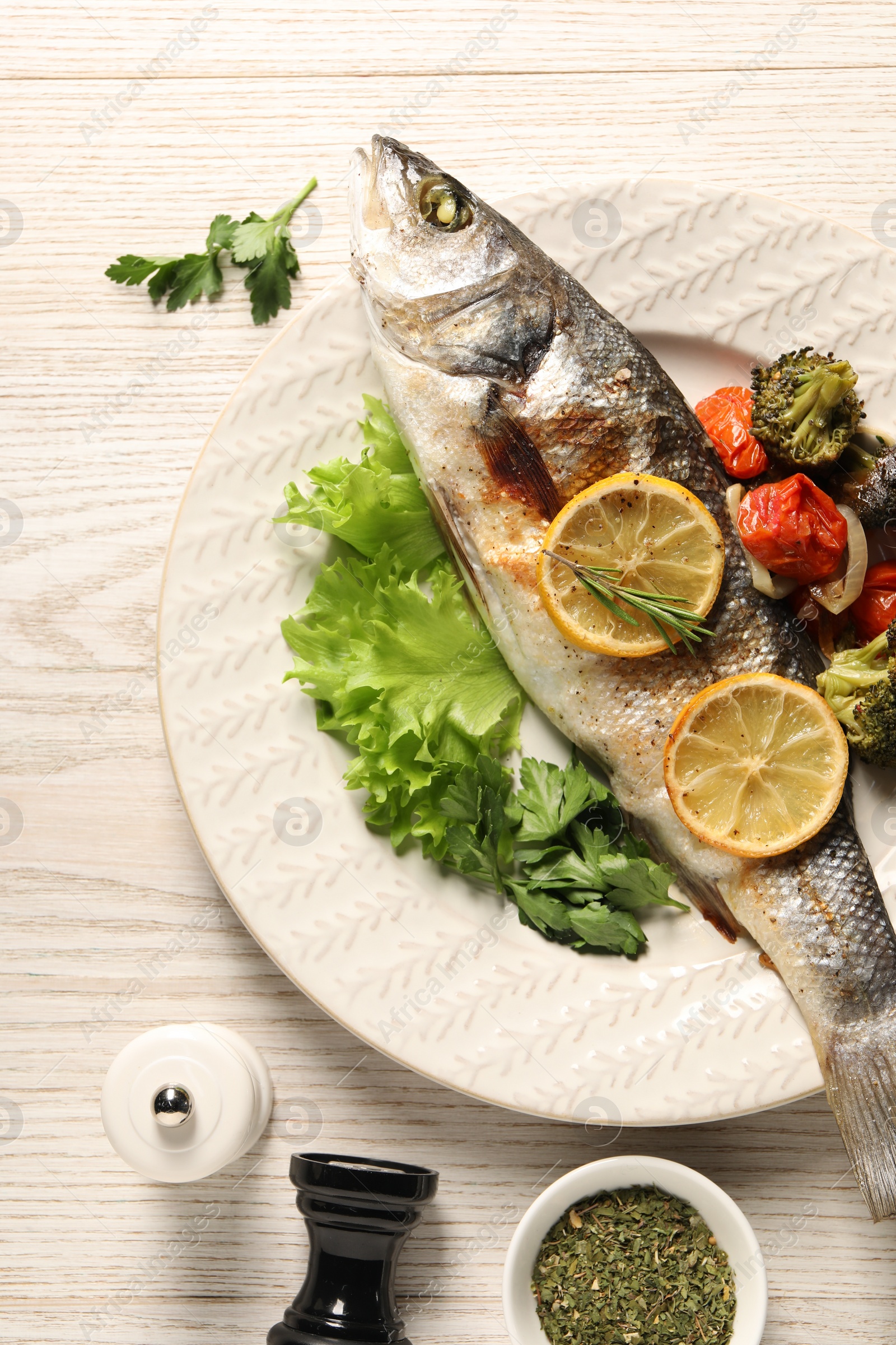 Photo of Delicious baked fish and vegetables served on wooden table, flat lay