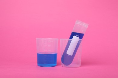 Photo of Beakers with test tube and liquid on bright pink background. Kids chemical experiment set