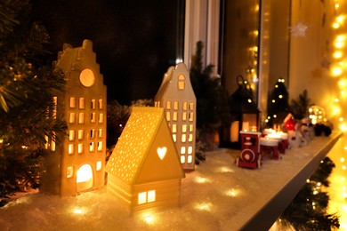 House shaped lanterns and Christmas decor on windowsill indoors, space for text