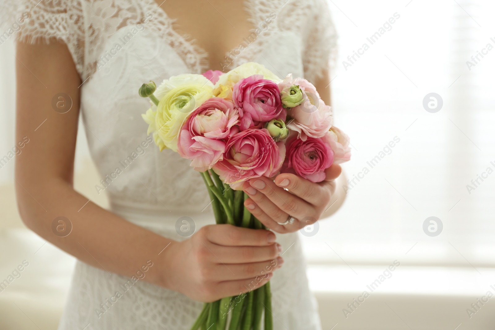 Photo of Bride with beautiful ranunculus bouquet indoors, closeup