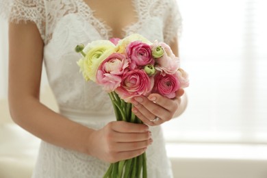 Photo of Bride with beautiful ranunculus bouquet indoors, closeup