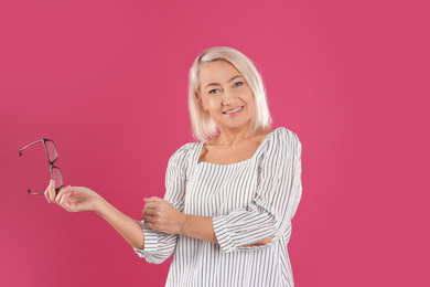 Photo of Portrait of beautiful mature woman with glasses on pink background