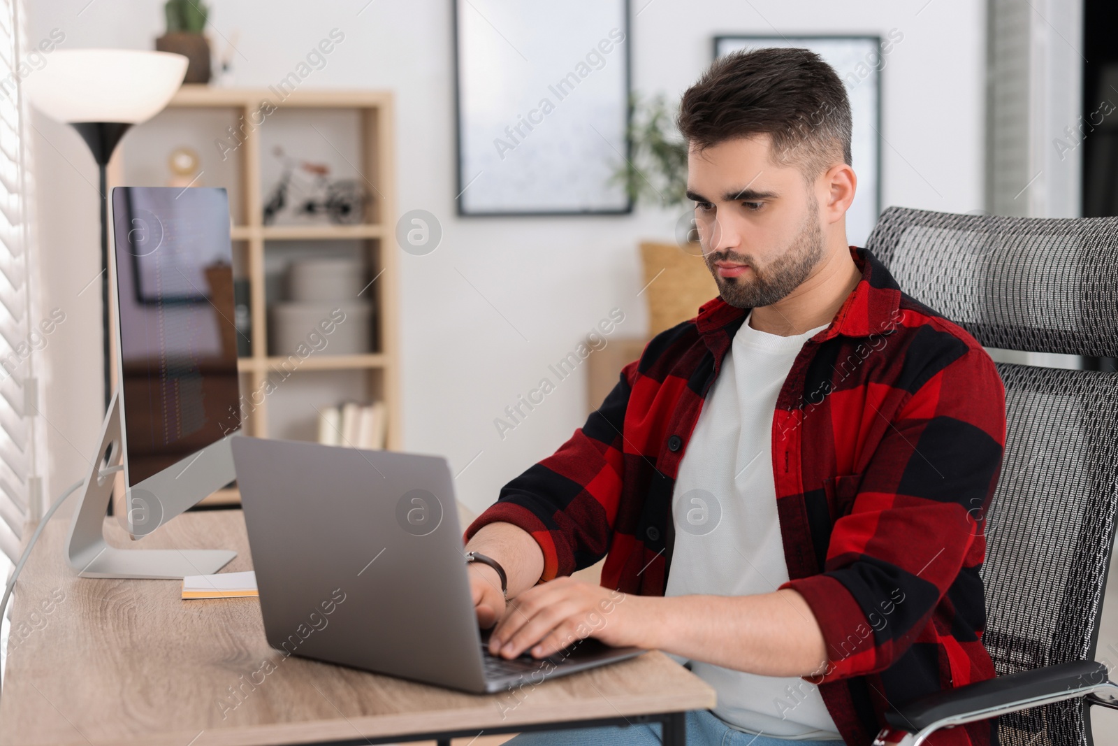 Photo of Young programmer working with laptop in office