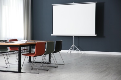 Photo of Modern meeting room interior with large table and projection screen