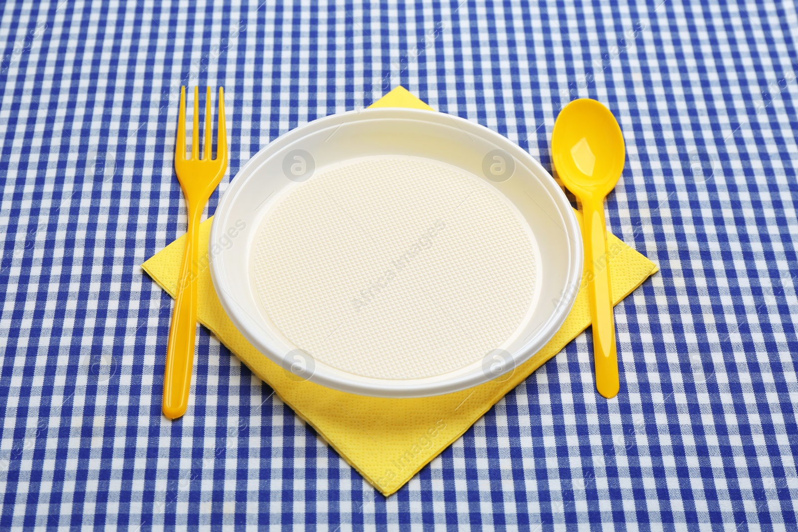 Photo of Table setting with plastic dishware on plaid fabric