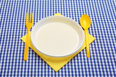 Table setting with plastic dishware on plaid fabric