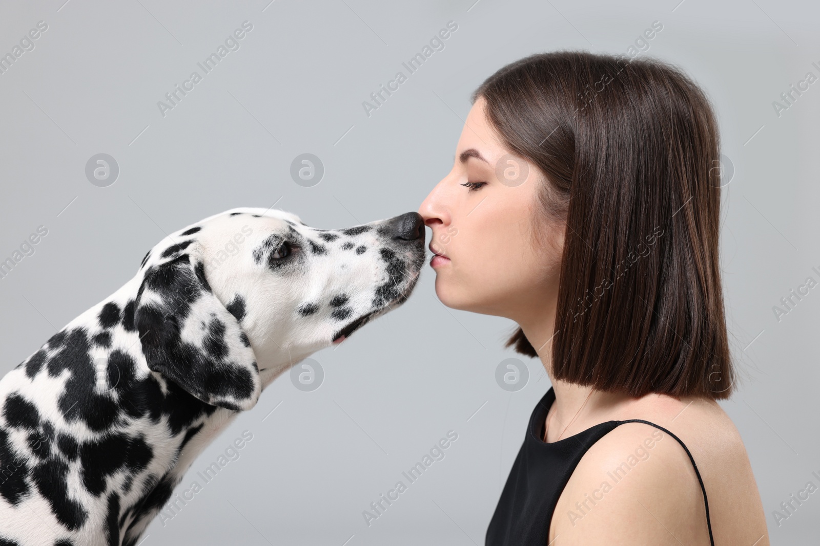 Photo of Beautiful woman with her adorable Dalmatian dog on light grey background. Lovely pet