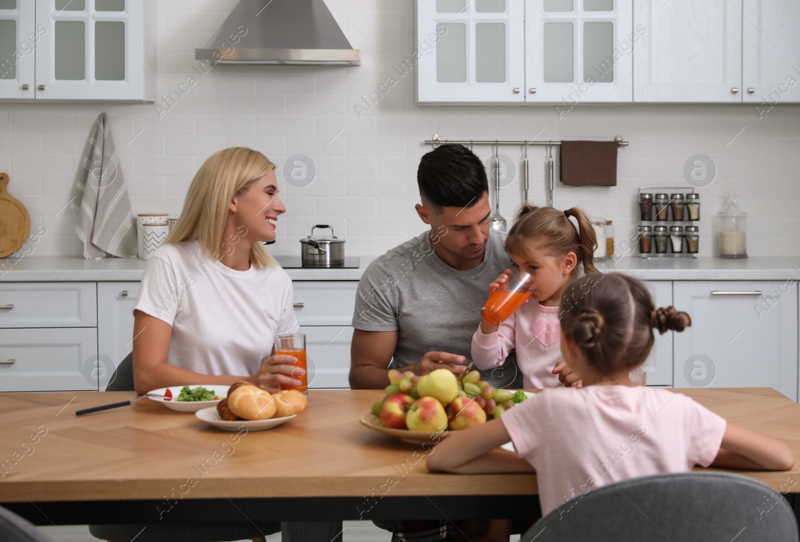 Photo of Happy family having breakfast together at table in modern kitchen