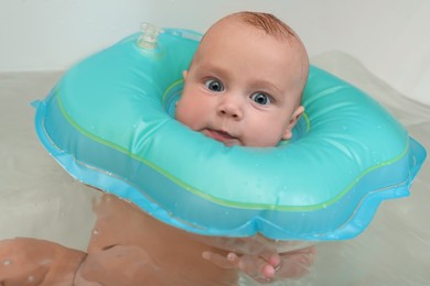 Photo of Cute little baby swimming with inflatable ring in bath