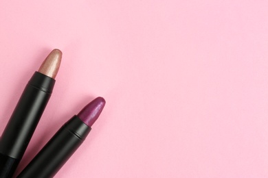 Photo of Bright lipsticks in black tubes on pink background, flat lay. Space for text