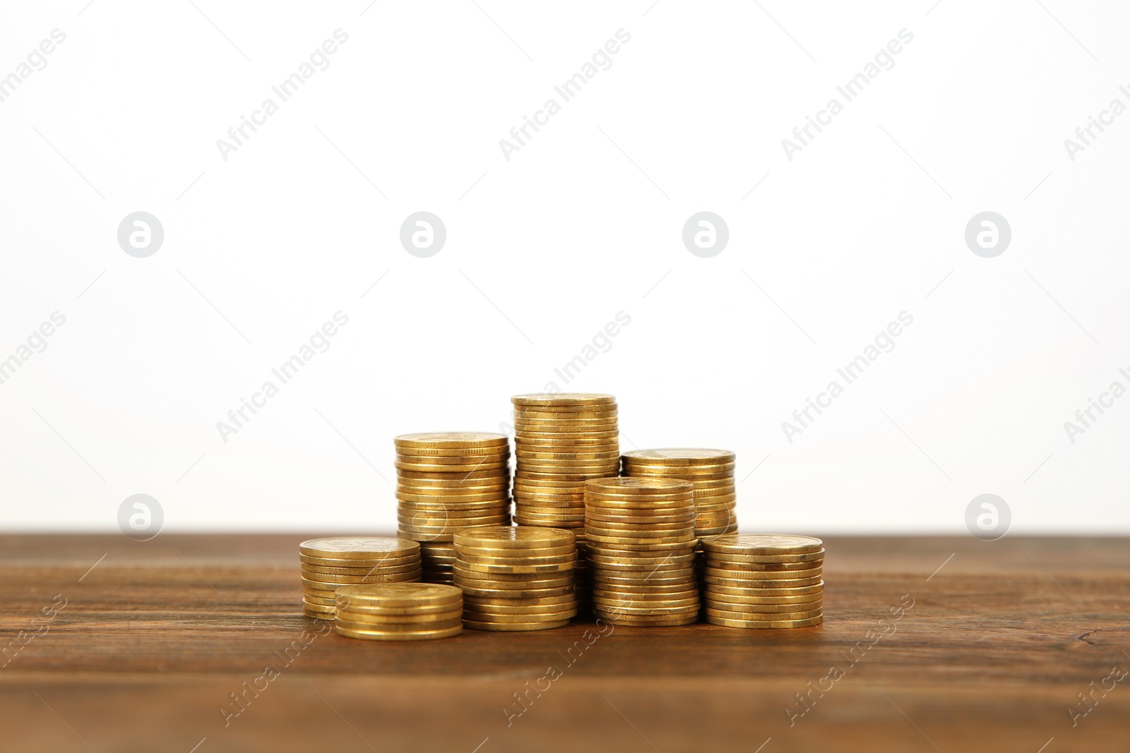 Photo of Many stacks of coins on table against light background