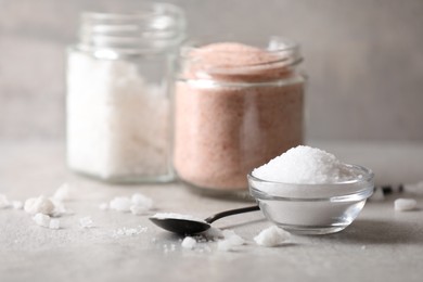 Photo of Different natural salt on grey table, closeup