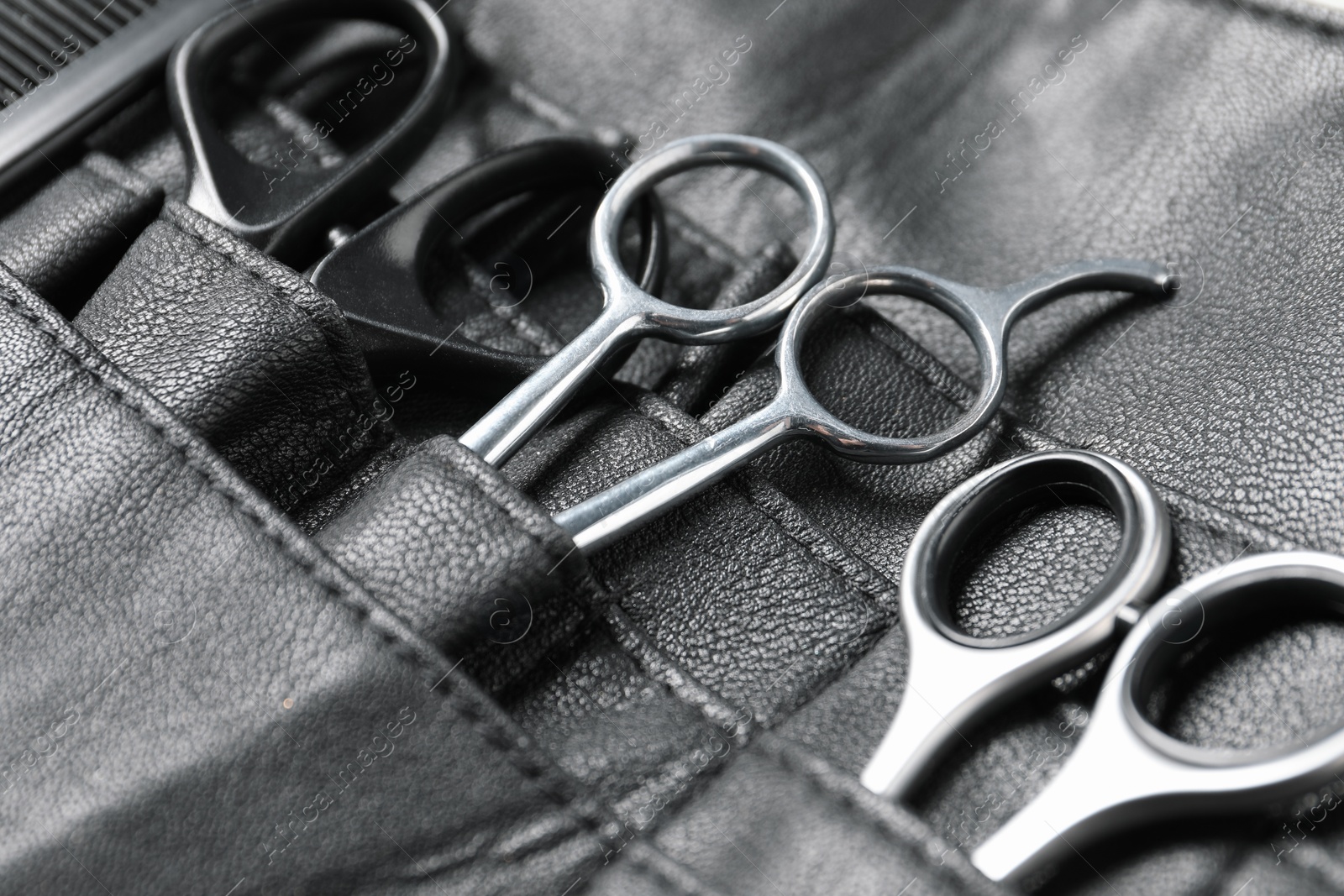 Photo of Hairdresser tools. Professional scissors in leather organizer, closeup