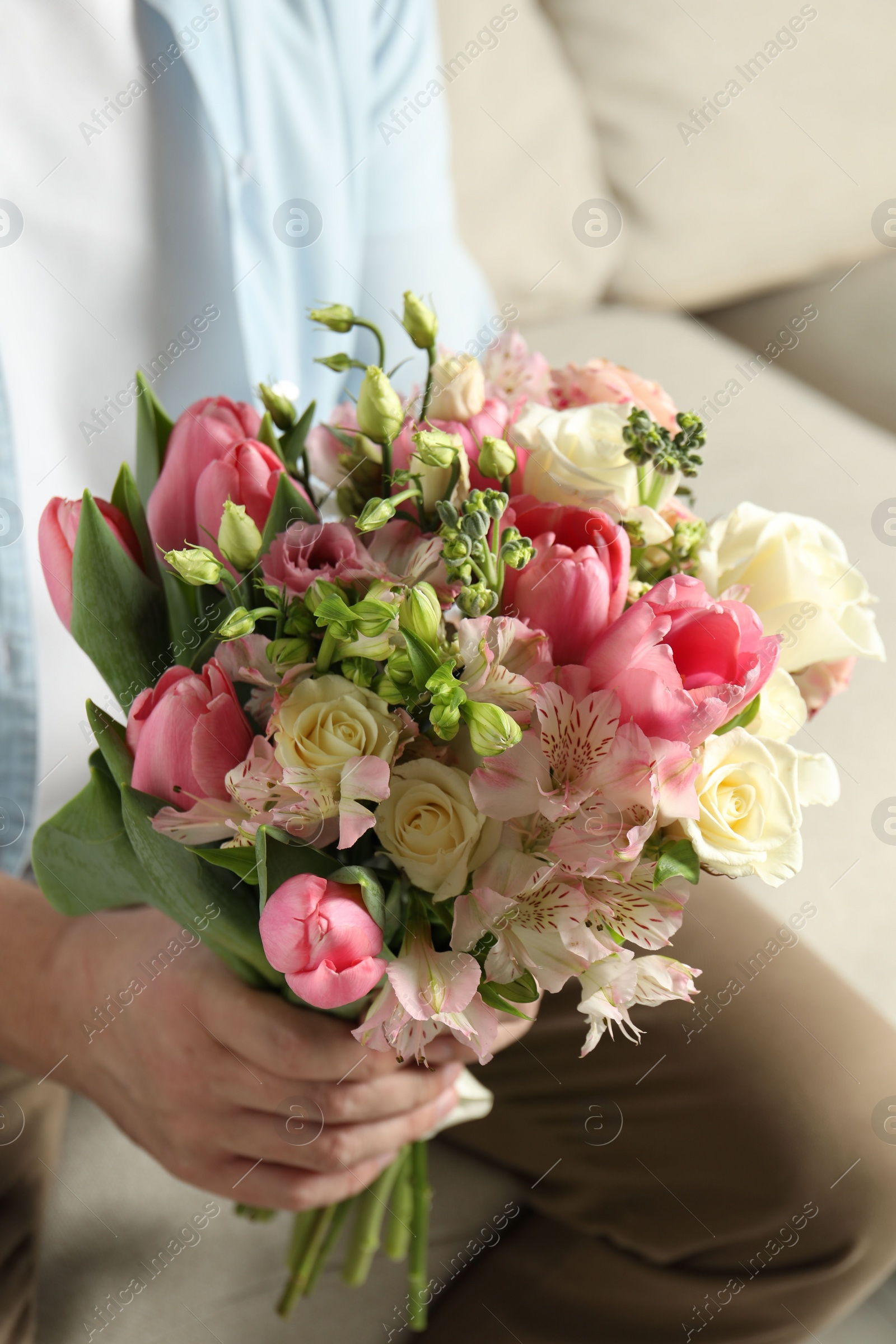 Photo of Man holding bouquet of beautiful flowers indoors, closeup