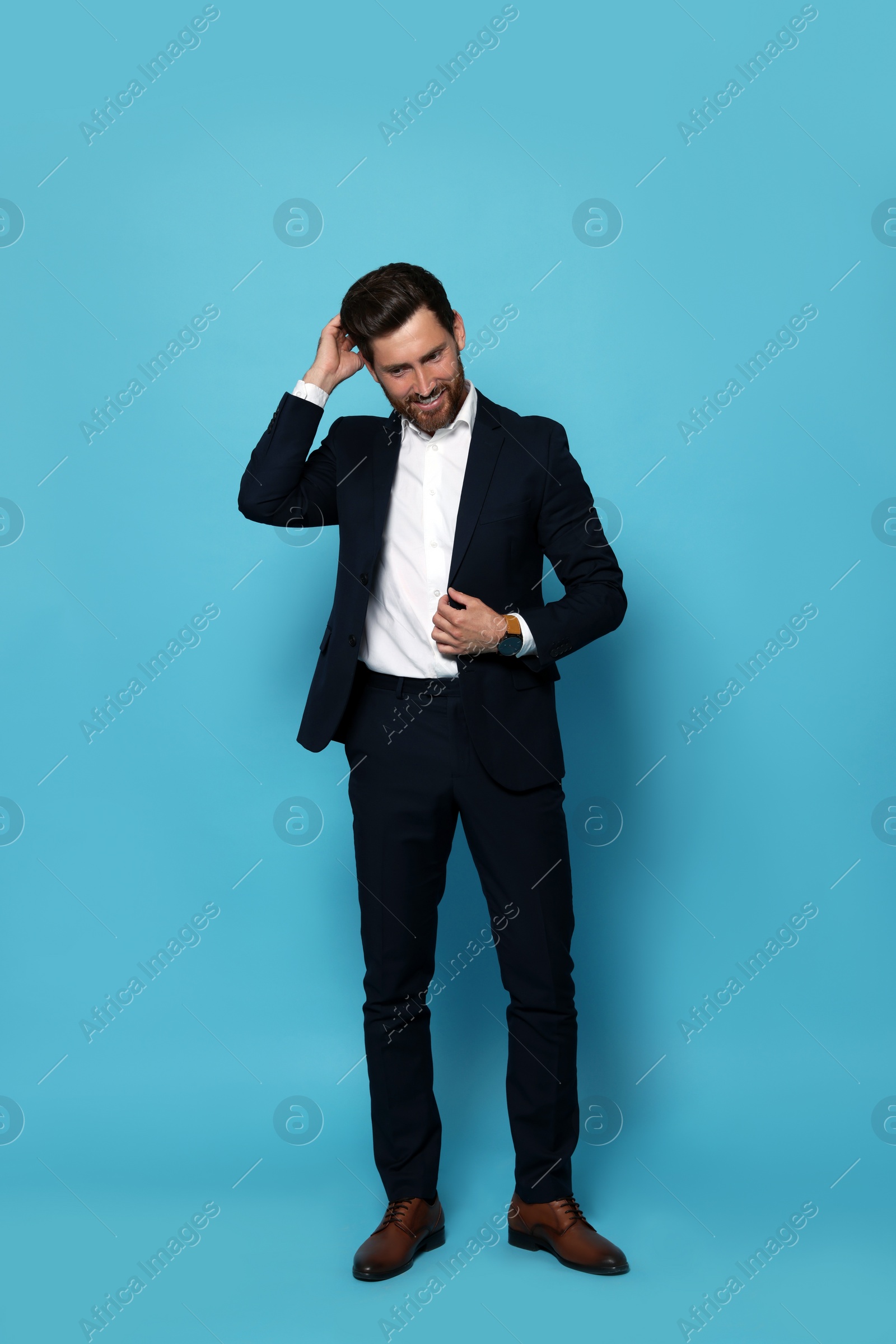 Photo of Smiling bearded man in suit on light blue background