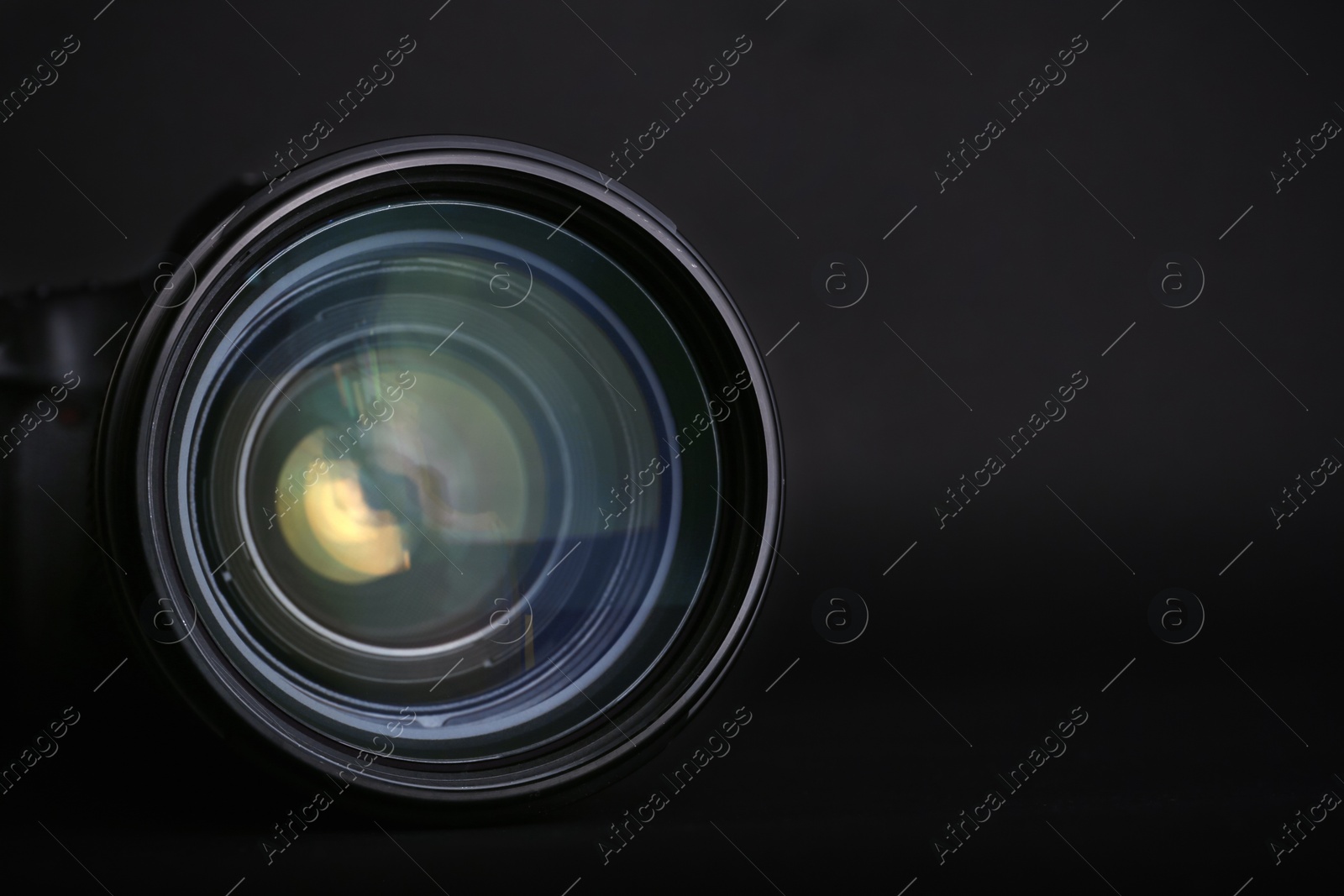 Photo of Modern camera lens on black background, closeup. Space for text