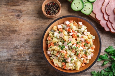 Photo of Delicious salad Olivier on wooden table, flat lay. Space for text