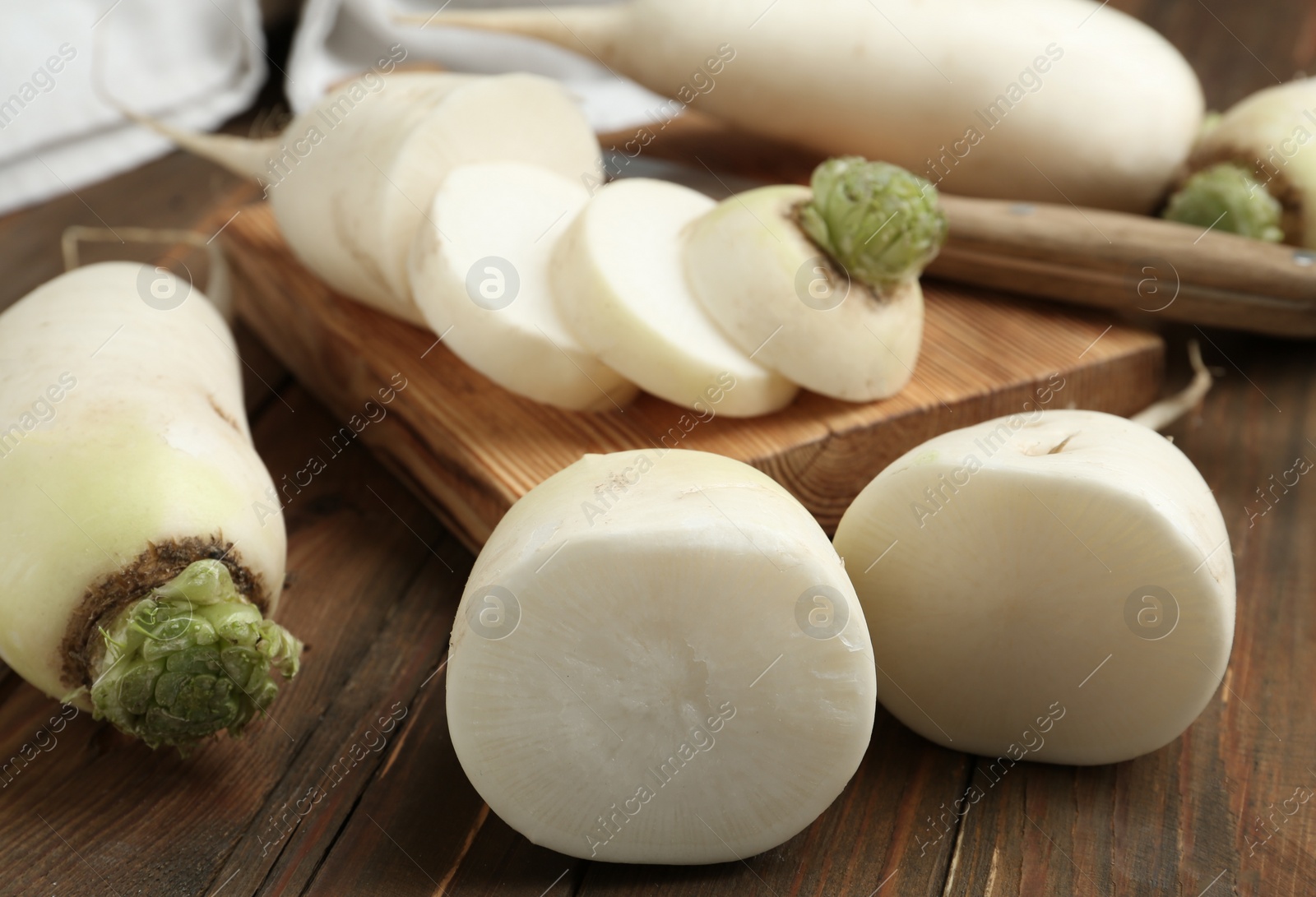 Photo of Cut and whole white turnips on wooden table, closeup