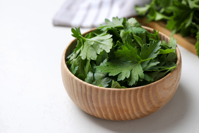 Photo of Fresh green parsley in wooden bowl on white table