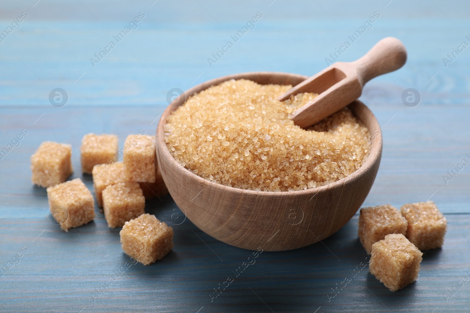 Photo of Different types of brown sugar on light blue wooden table