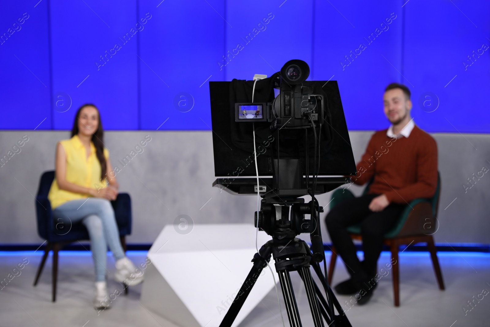 Photo of Presenters working in studio, focus on video camera