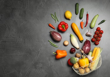 Flat lay composition with different vegetables and basket on grey background. Space for text