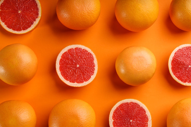 Cut and whole ripe grapefruits on orange background, flat lay