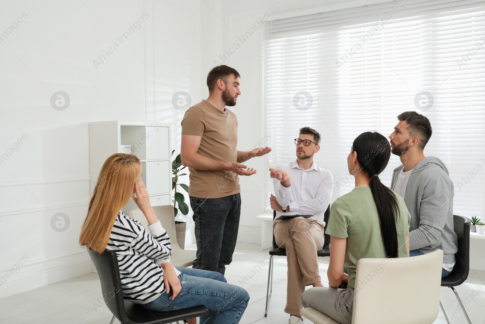 Photo of Psychotherapist working with group of drug addicted people at therapy session indoors